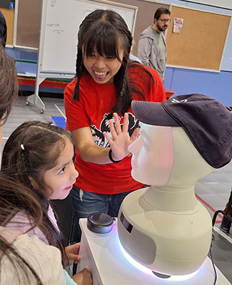 Yen-Jung Chen shows the Furhat to a young STEM Fest visitor.