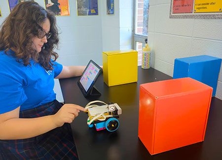 Seventh-grade student Makenzie programs movement commands for the LEGO car.