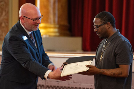 Jim Ahern, dean of the Graduate School, presents the certificate for the Diversifying Higher Education Faculty in Illinois Fellowship to Aaron Malone.